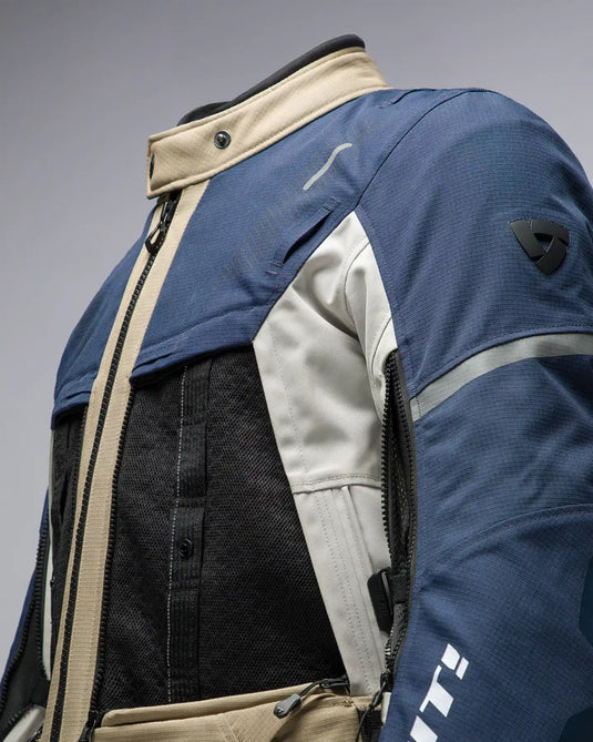 Una chaqueta de textil azul, beige y negra para motocicleta con ventilación de malla y detalles reflectantes.