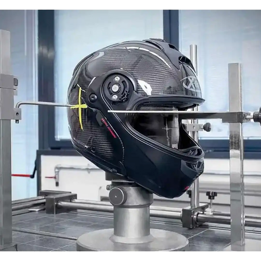 Casco de motocicleta de fibra de carbono con un gráfico en forma de 'X' amarillo.