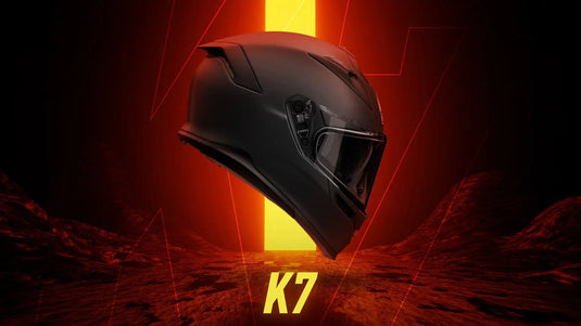 Casco de moto negro mate con diseño aerodinámico elegante y visera integrada.
