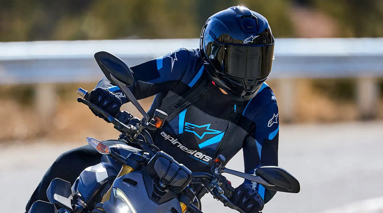 Un motorista con un traje de carreras negro y azul y casco.