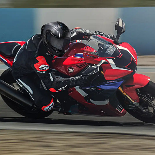 Motocicleta deportiva Honda roja y negra con un piloto con un traje de carreras.